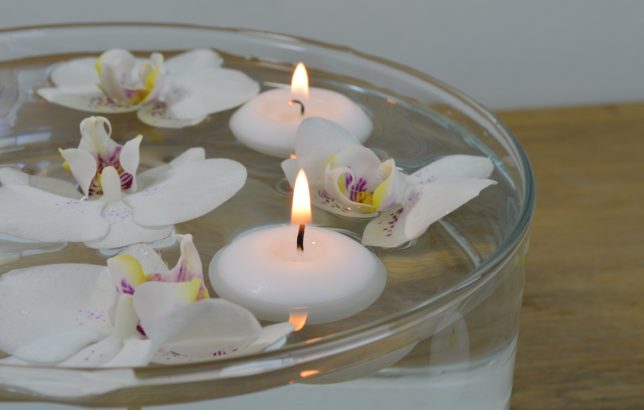 White and purple orchids with candles floating in a bowl of water